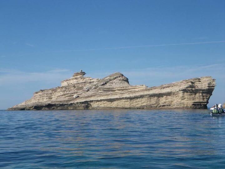 Roca con forma de barco situada frente a la orilla del mar.