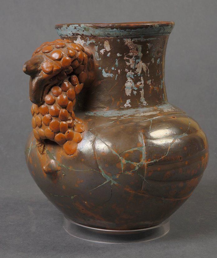 Recipiente con forma de jarrón con asa con cabeza de pavo.