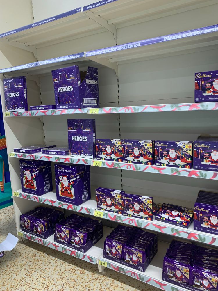 The image depicts shelves of Cadbury’s Christmas selection boxes 