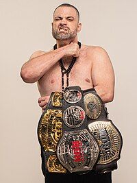 Professional wrestler Eddie "Mad King" Kingston with three title belts