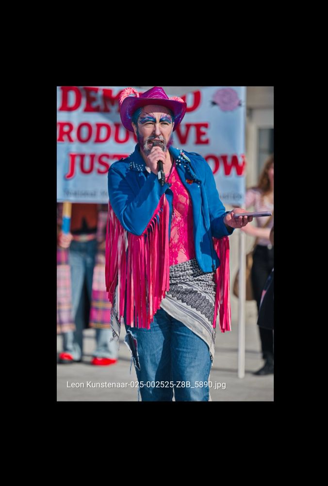 a trans color coded cowboy with horns coming out of his head (the bussed in opposition already pictures me with horns I might as well wear them) speaks into a microphone telling the “walk for life” “Christian” nationalists some hard truths 
