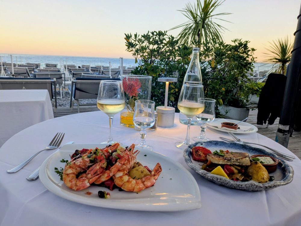 Vitt vin och god mat (grillade skaldjur och svärdfisk) vid stranden i Nice. 