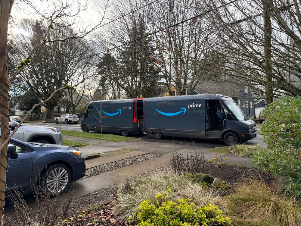 Two Amazon prime trucks, backed up so their rear ends are almost touching