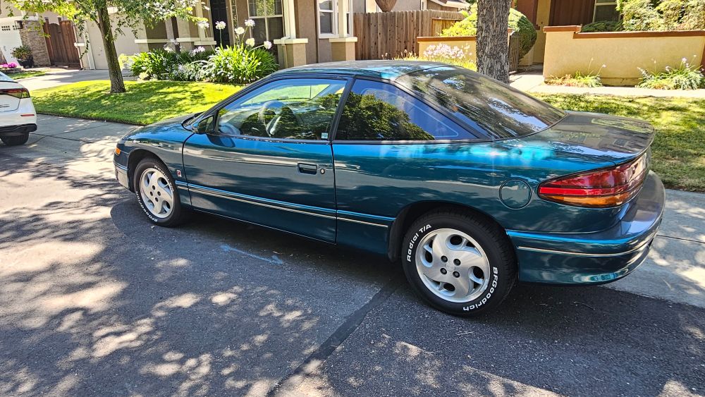 Driver's side of a Saturn SC coupe, in green. 