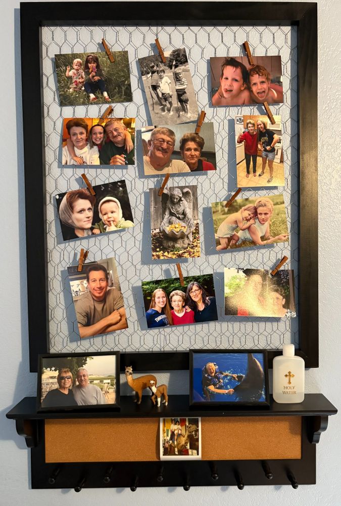 Detail of a chicken wire frame with photos clipped to it and a shelf with two framed photos and mementos of lost loved ones.