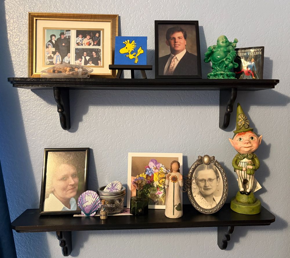 Detail of two shelves with framed photos and mementos of lost loved ones.