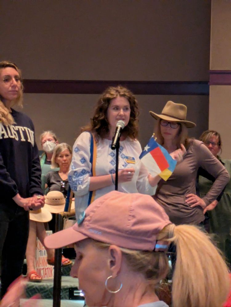 A woman from Ukraine holds a Texas and a Ukrainian flag as she shares her concerns over Senator John Cornyn's silence in the face of possible loss of U.S. military support for her country that is currently besieged by Russia