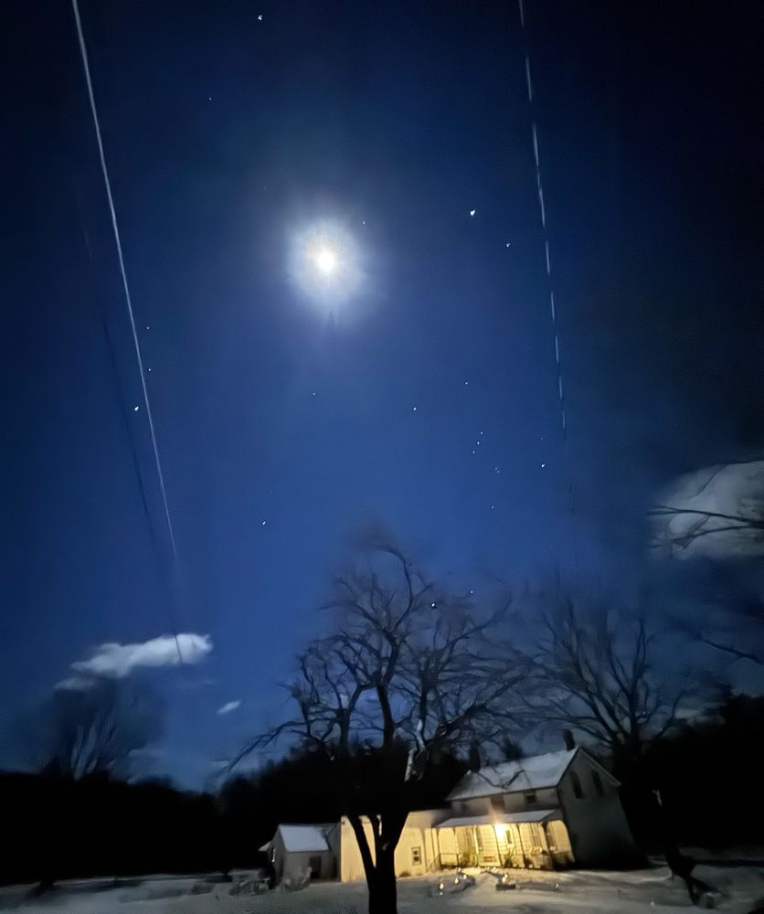 A picture of the moon shining over a house
