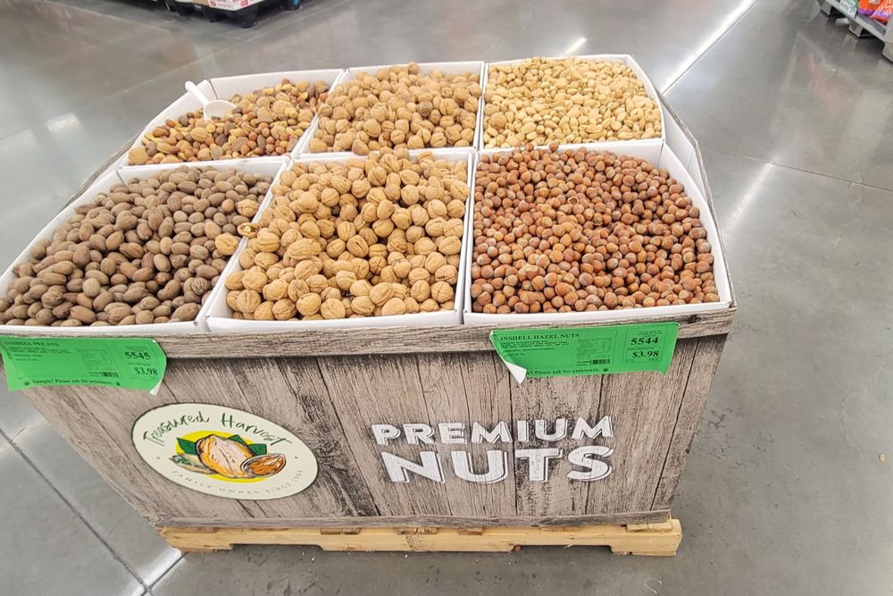 An in-grocery store display of a crate containing six varieties of assorted tree nuts.