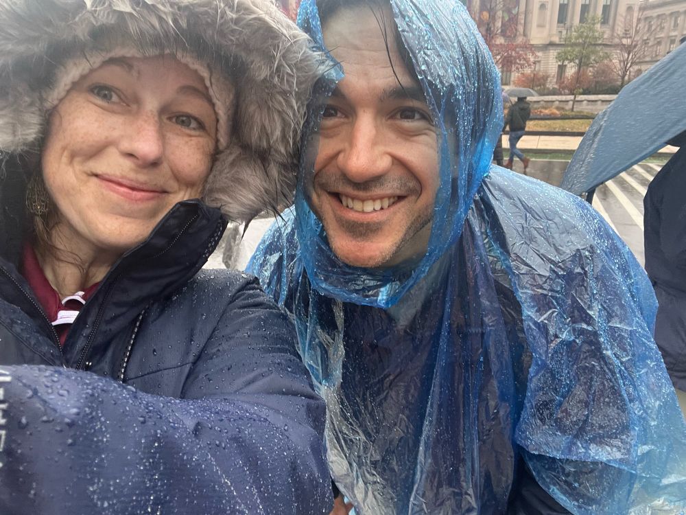 Two people wearing rain ponchos and jackets soaking wet on the streets of Phili for the parade. 