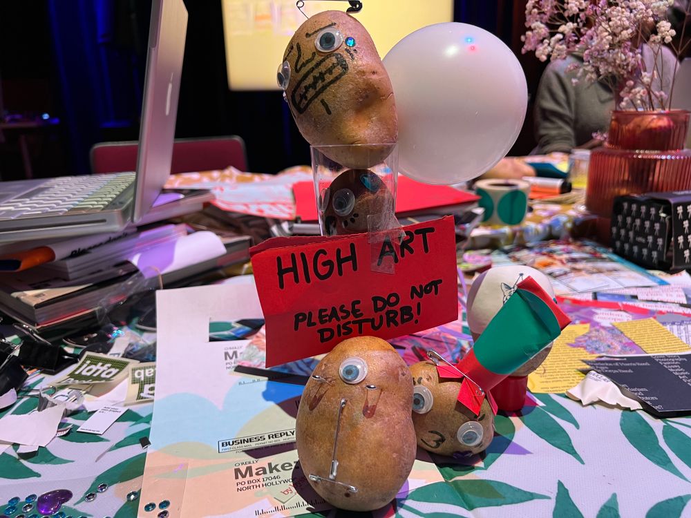 a photo of a pile of potatoes with googly eyes. a sign states that they are art and mustn’t be disturbed.