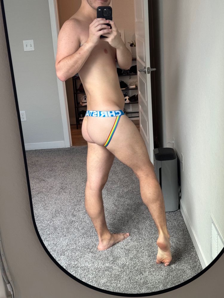 Photo of me just in a rainbow Andrew Christian jockstrap. This view focuses on my ass and legs.