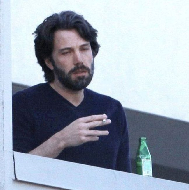 meme image of Ben Affleck looking tired af while smoking, with a bottle of alcohol? beside him