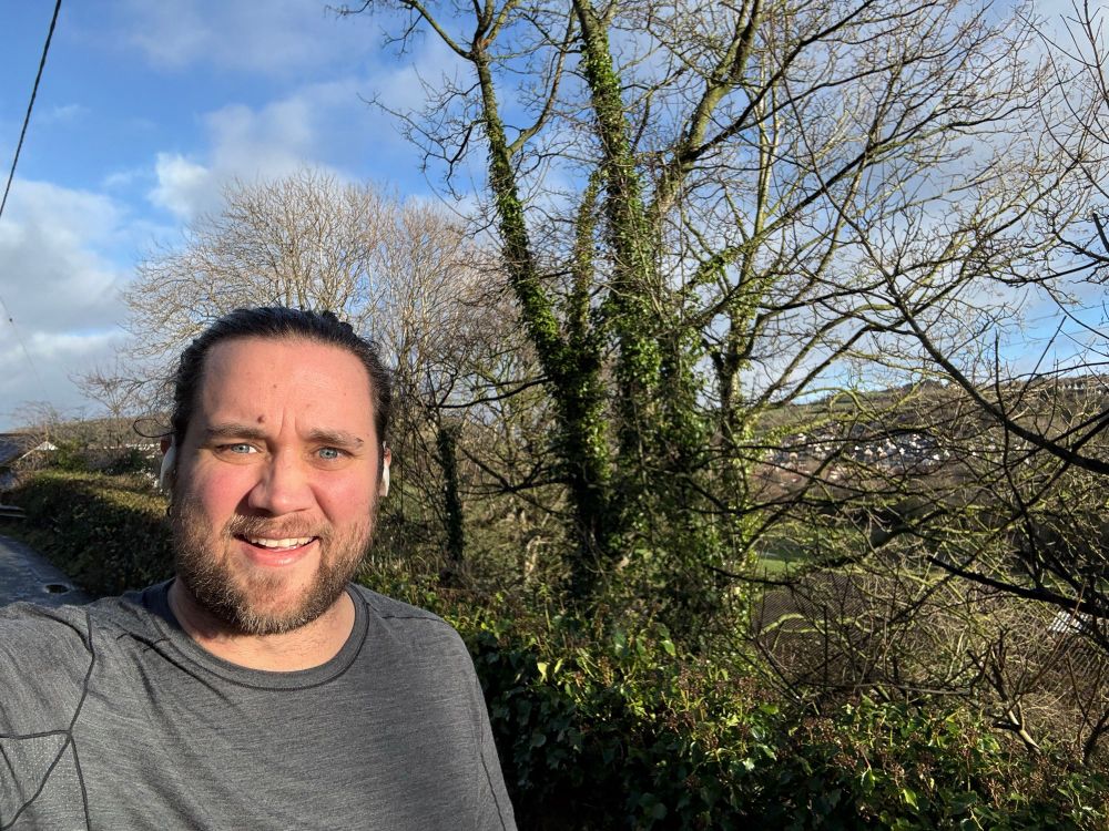 Smiley man with trees and blue cloudy skies in the background 