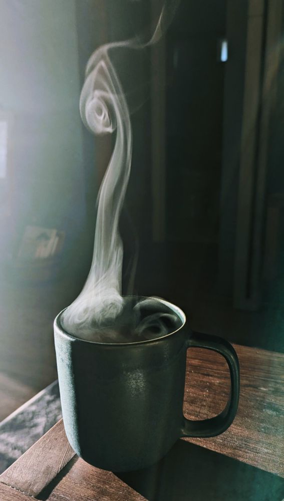 Steam from a cup of hot coffee creating a swirling pattern 