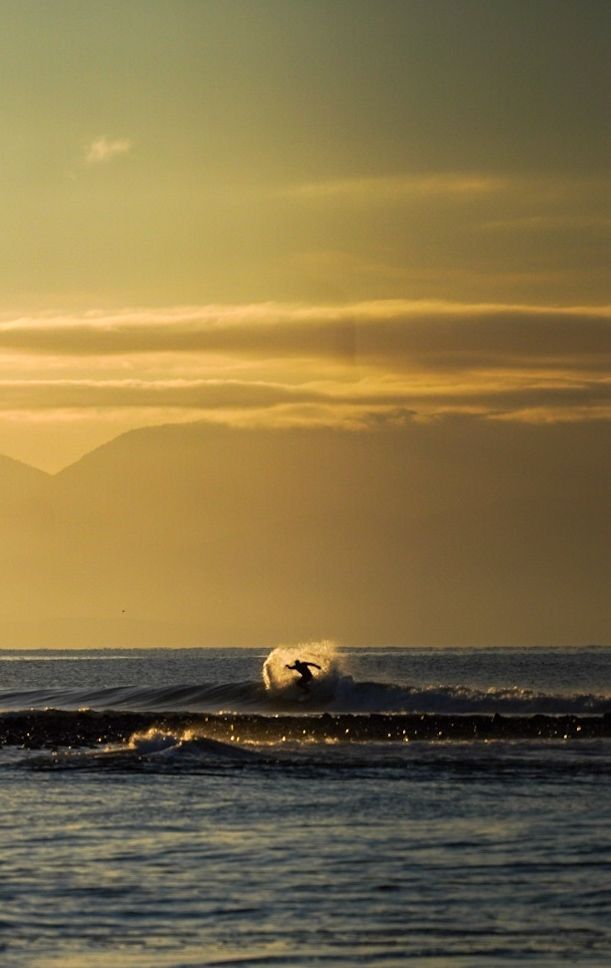 A surfer in Jordan River, BC, backlit by the sunrise on Jan 21, 2024.