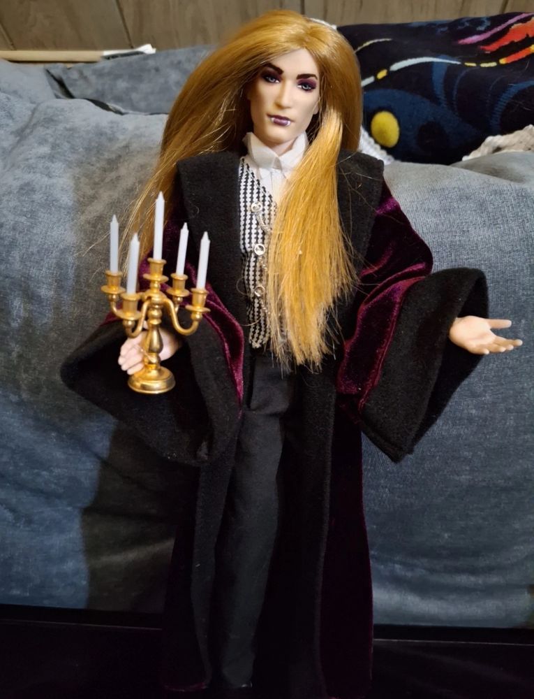 Ken doll with rerooted blond hair holding a candelabra and dressed as a VAMPIRE 