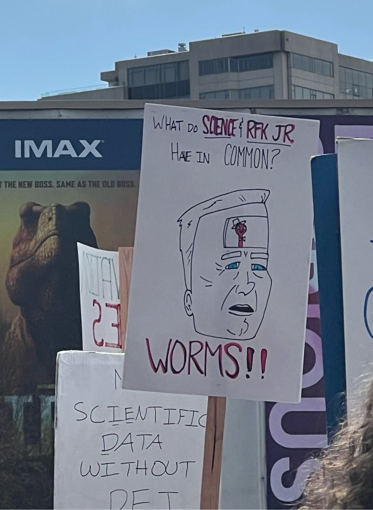 A sign that says “What do Science & RFK Jr. have in common? Worms!!”