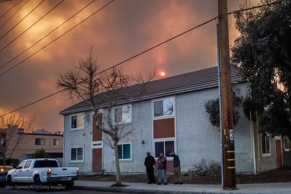 Local residents stand outside their home as the sky is filled by smoke in Castaic. Photo by Apu Gomes for Getty Images.