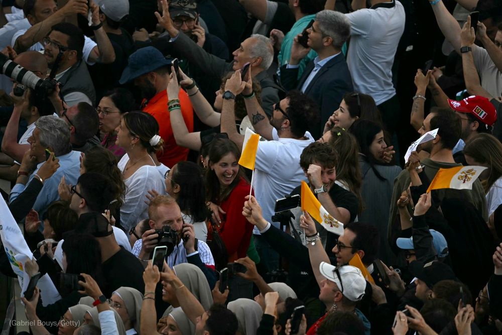 People cheer as white smoke (unseen) signals that cardinals elected a new pope during their conclave in the Vatican on May 8, 2025. Photo by Gabriel Bouys for Getty Images.
