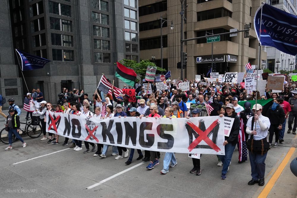 Protestors hold a banner reading, "NO KINGS" as they march in Chicago.
