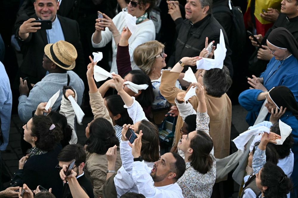 People react and wave Vatican flags as white smoke (unseen) signals that cardinals elected a new pope during their conclave in the Vatican on May 8, 2025. Photo by Gabriel Bouys for Getty Images.
