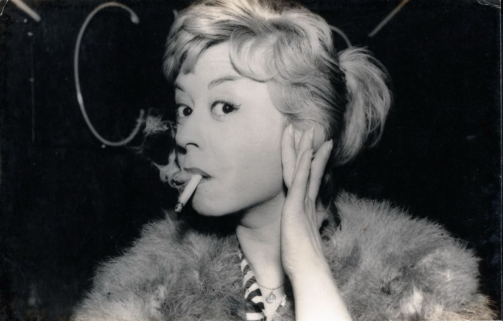 Black and white photo of Giulietta Masina as Cabiria with her fur shawl and a lit cigarette in her mouth 