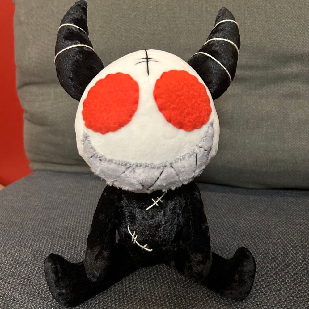 My Alastor poppet plushie, sitting on my couch. You can really see the velour texture of the body in this one!