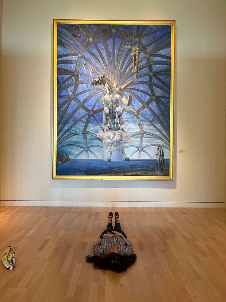 Woman lying on the floor of the Beaverbrook Art Gallery looking up at a large Salvador Dali painting. This is how it is supposed to be viewed. 