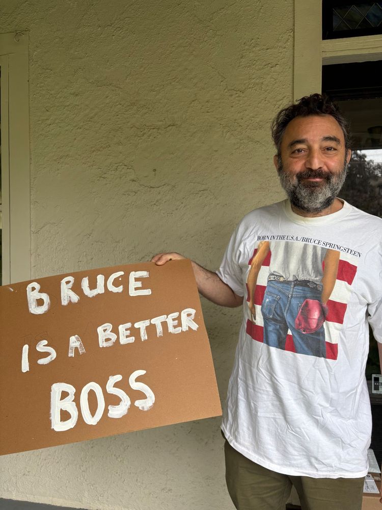 Me holding a sign saying "Bruce is a better boss" with a Bruce born in the USA t-shirt 