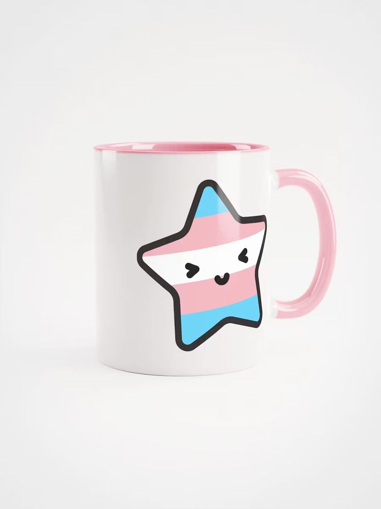 A white mug with a pink handle and Gleam's super cute cartoon starfish mascot on the side, coloured with the trans flag pattern.