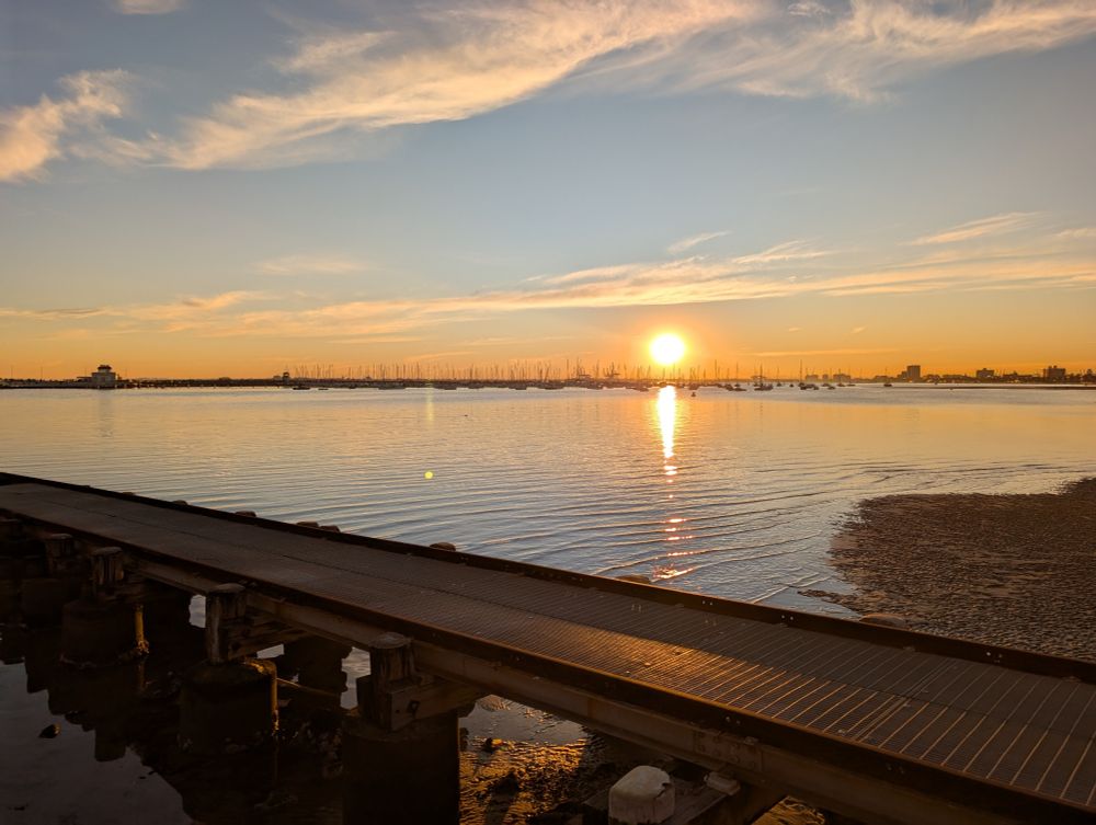 Sun setting on Port Phillip Bay over a boat ramp