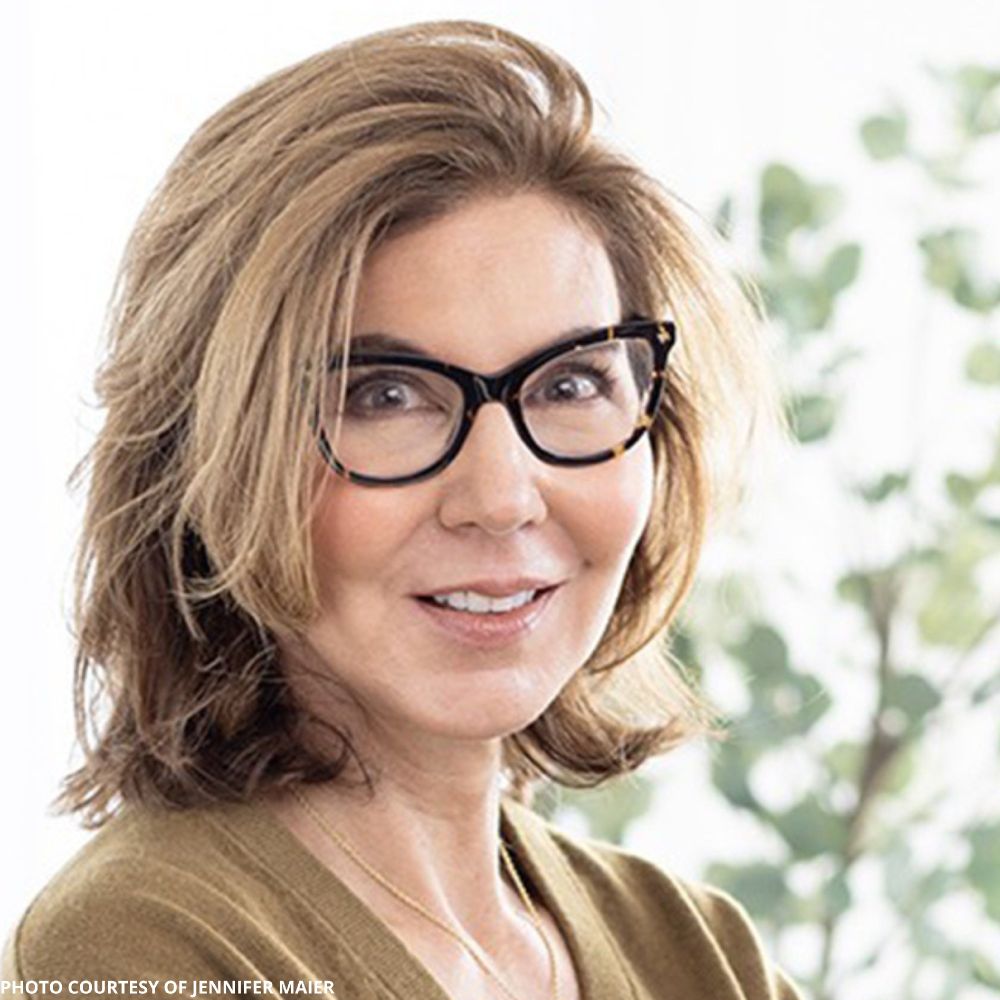Photograph of poet Jennifer Maier. She has shoulder-length light brown hair and wears cat-eye-rimmed glasses.