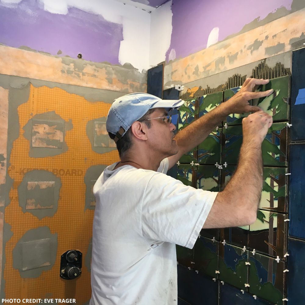 A photograph of poet Bob Hicok. He is working on a construction project and wearing a white t-shirt and baseball cap.
