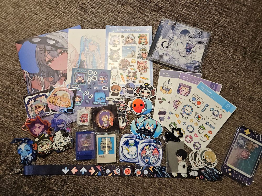 A photo of an assortment of merchandise from various fandoms, including Hololive, Vocaloid, Project Sekai and Maimai