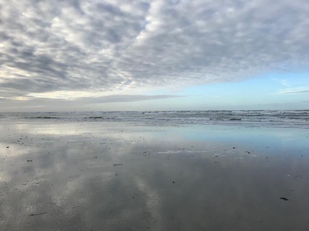 Das Foto zeigt das Meer bei Ebbe. Es wurde am Billriff auf der Insel Juist aufgenommen. Besonders ist ein monochromer Farbverlauf von Grau- und Blautöne. Der wolkige Himmel spiegelt sich im feuchten Watt.