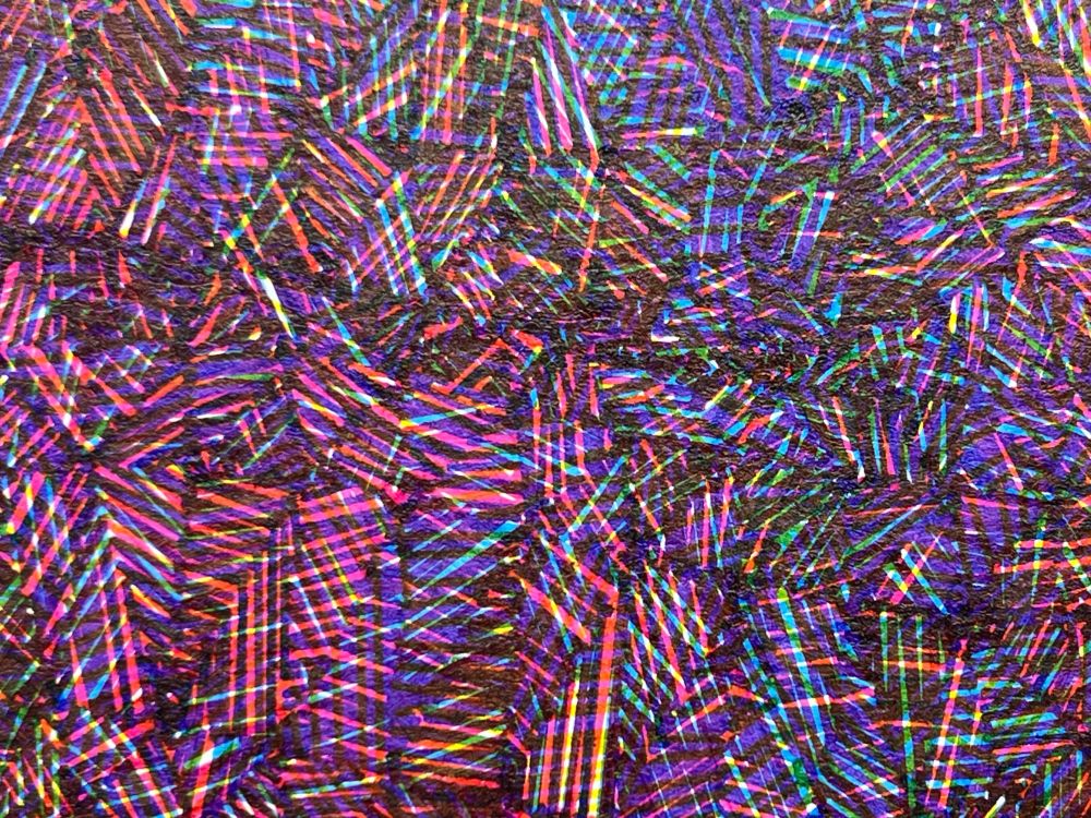 Detail from an abstract pen plot on white paper in portrait orientation of tightly packed triangles arranged in a subtle wave pattern from upper left to lower right each hatch shaded with a different color from overlapping cyan, yellow, and magenta inks.  The shading is disorganized so it has a shaggy, fuzzy texture about it. The detail shows individual pen strokes comprising the hatch shading.