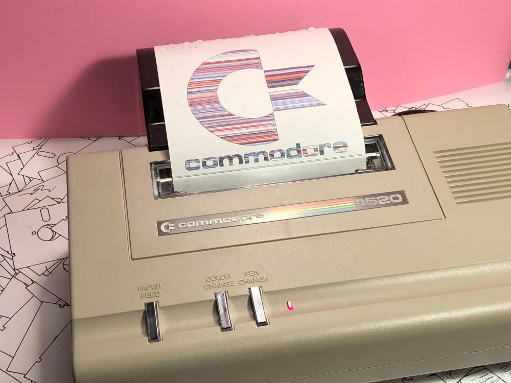 A Commodore 1520 pen plotter with 4” wide paper and a color stripped Commodore logo printed on it. 