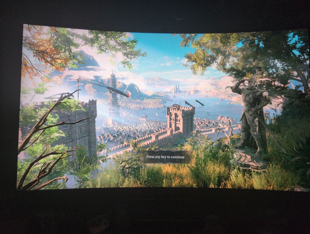 Opening screen for Baldur's Gate 3. Overlooking a city from a hill with large castle walls. A statue of a soldier is in the foreground. 