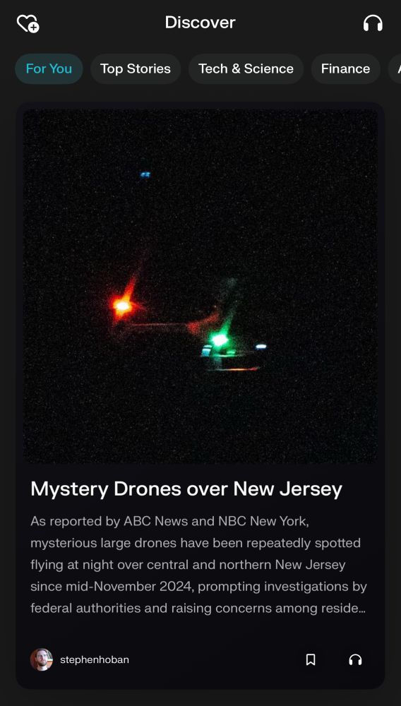Screenshot of a news article in the “Discover” section titled “Mystery Drones over New Jersey.” The image shows a dark sky with faint lights, including red and green, likely from a drone. The article preview reads: “As reported by ABC News and NBC New York, mysterious large drones have been repeatedly spotted flying at night over central and northern New Jersey since mid-November 2024, prompting investigations by federal authorities and raising concerns among residents…” Below the text, there’s an author tag with the name “stephenhoban” and icons for saving or listening to the article.
