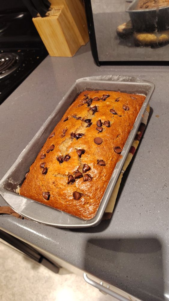 A pan of fresh banana bread, topped with a handful of chocolate chips. It was just pulled out of the oven. 