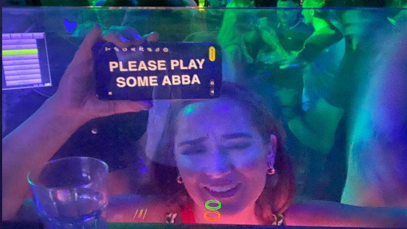 Girl with her phone saying "please play some ABBA"