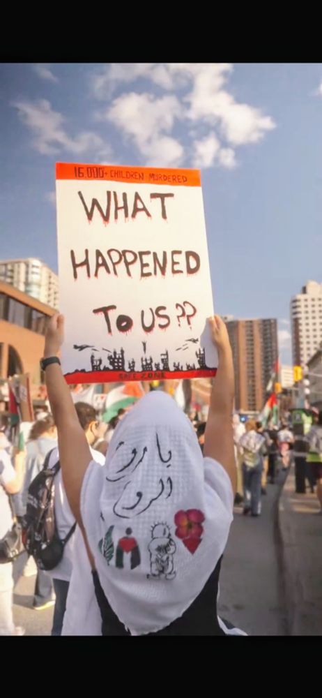 Screenshot from video showing someone holding up a sign "What happened to us?"