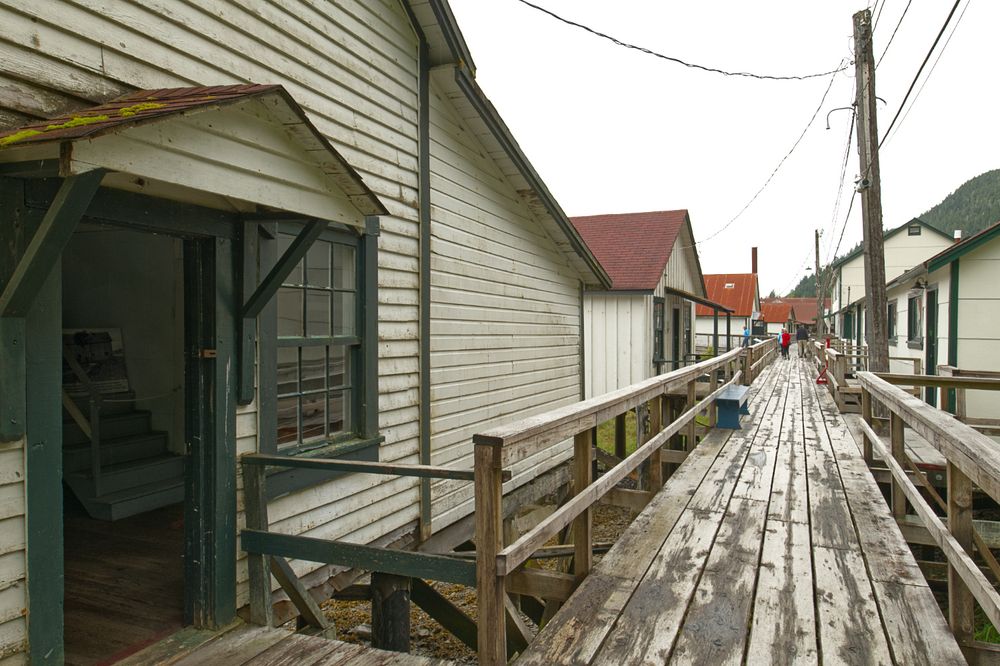 The exterior of a simple, wooden building scarcely more than a shed. The walkway in front is a wooden boardwalk. It leads to other, similarly modest wooden buildings.