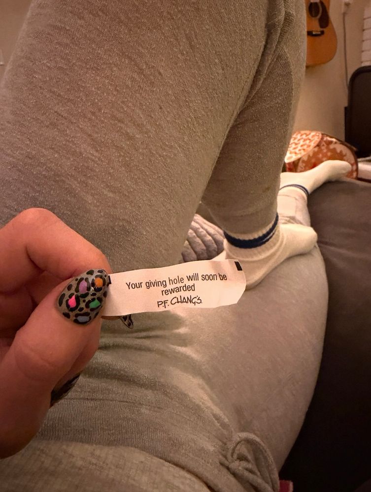 Siri holding a fortune from a PF Chang’s fortune cookie that says “Your giving hole will soon be rewarded.”