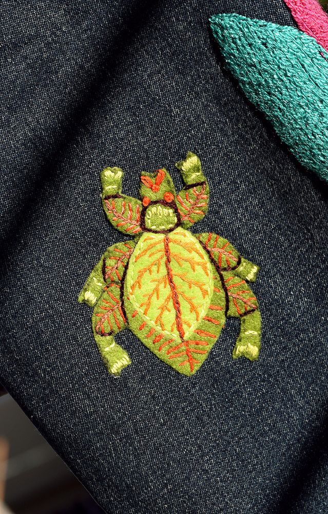 A hand embroidered patch of a green leaf bug (or Phyllium if you want the fancier name lol). It got ironed to a pair of jeans