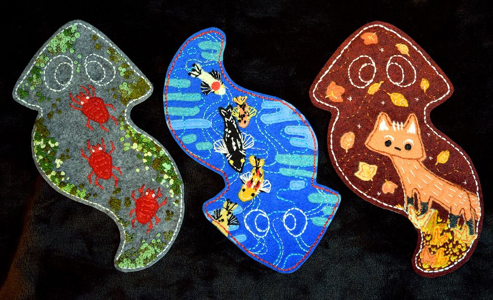 A picture of three planaria patches, they have different motifs and illustrations in them