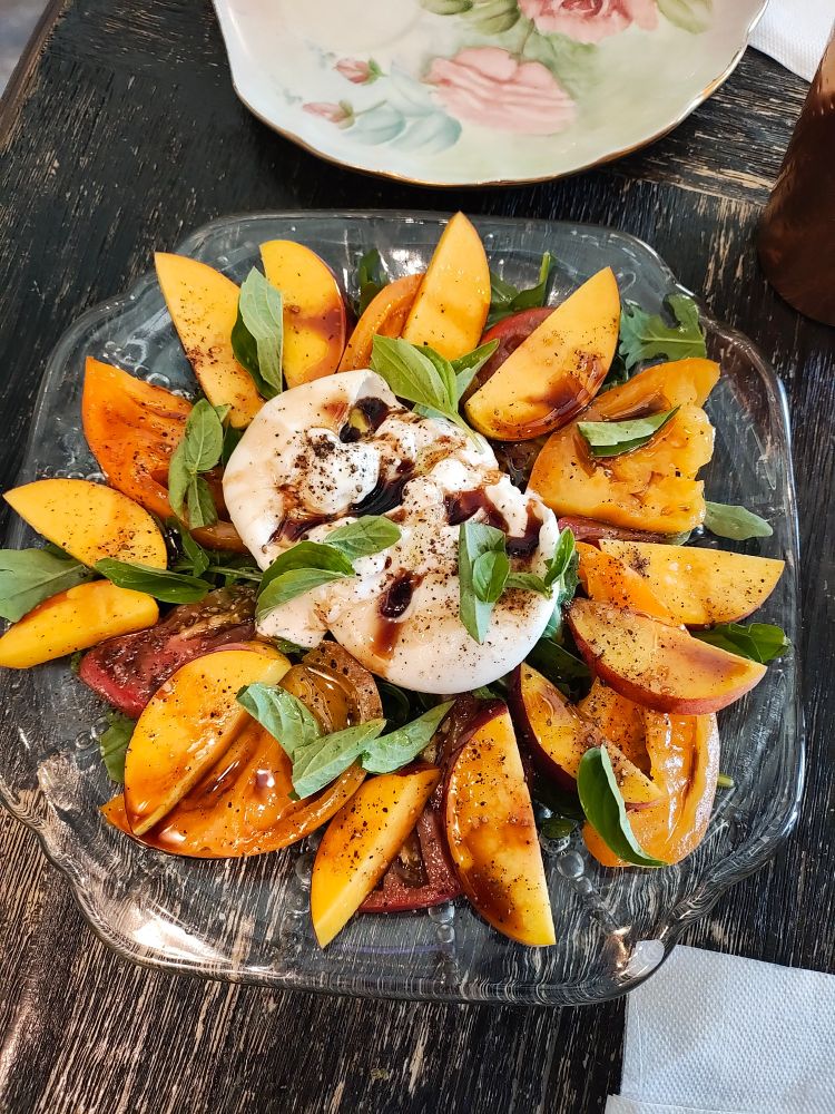Photo of burrata salad with heirloom tomatoes, fresh basil and nectarines in a balsamic vinaigrette 