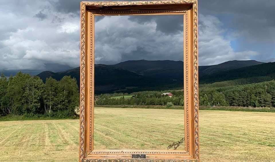 Das Foto zeigt eine ländliche Region in Norwegen. Jemand hat einen Bilderrahmen aufgestellt. Dieser unterstreicht die malerische Landschaft. Vermutlich nutzen ihn Leute um Fotos von sich selbst darin zu machen.