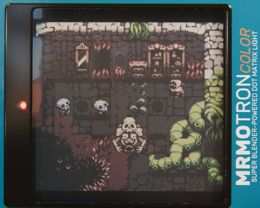 3D render of what looks like a vintage color LCD device showing a strange room with skeletal entities and sprawling tentacles.